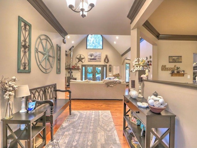 interior space featuring ornamental molding, lofted ceiling, wood finished floors, and a chandelier