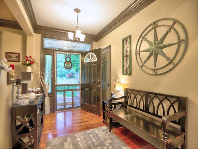 entrance foyer featuring a notable chandelier, ornamental molding, and wood finished floors
