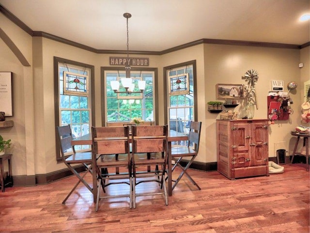 dining area with baseboards, ornamental molding, and wood finished floors