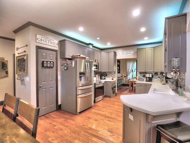 kitchen featuring a peninsula, a breakfast bar, tasteful backsplash, a sink, and appliances with stainless steel finishes
