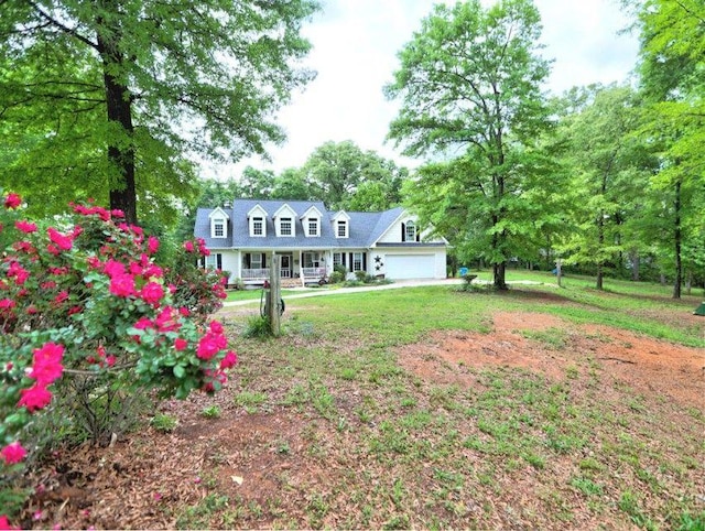 rear view of property with a porch, an attached garage, and a yard