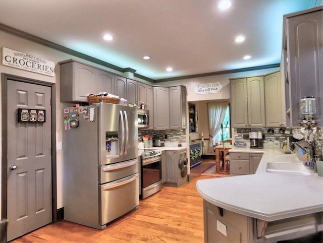 kitchen with ornamental molding, recessed lighting, light countertops, appliances with stainless steel finishes, and backsplash