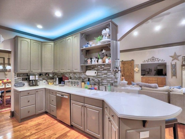 kitchen featuring a sink, light wood finished floors, dishwasher, backsplash, and ornamental molding