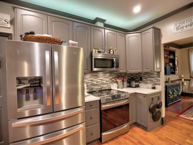 kitchen featuring decorative backsplash, appliances with stainless steel finishes, light wood-type flooring, gray cabinetry, and light countertops