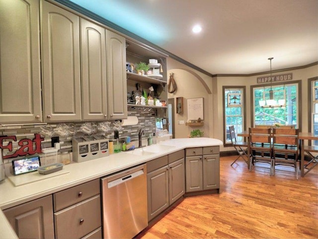 kitchen featuring decorative backsplash, gray cabinets, crown molding, dishwasher, and a sink
