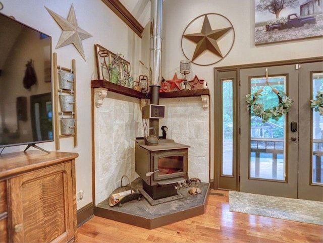 entrance foyer featuring french doors, a wood stove, wood finished floors, and a wealth of natural light