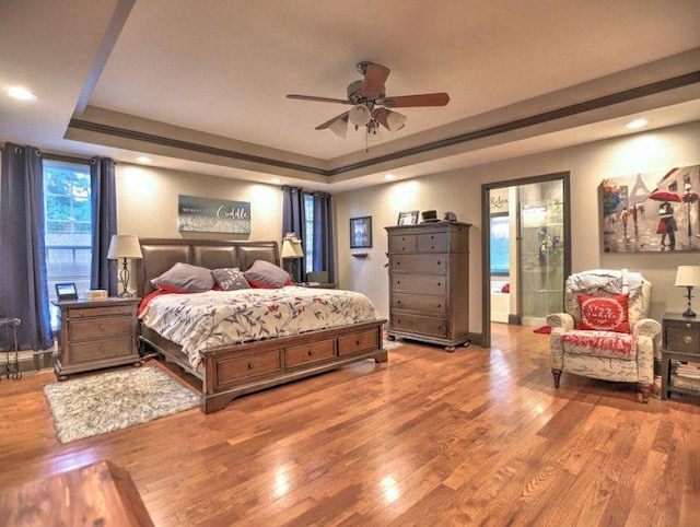 bedroom featuring ceiling fan, a tray ceiling, recessed lighting, and wood finished floors