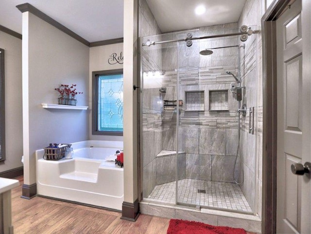 bathroom featuring ornamental molding, a garden tub, a stall shower, and wood finished floors