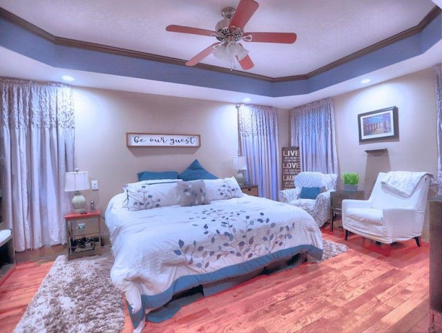 bedroom with crown molding, a raised ceiling, recessed lighting, and wood finished floors