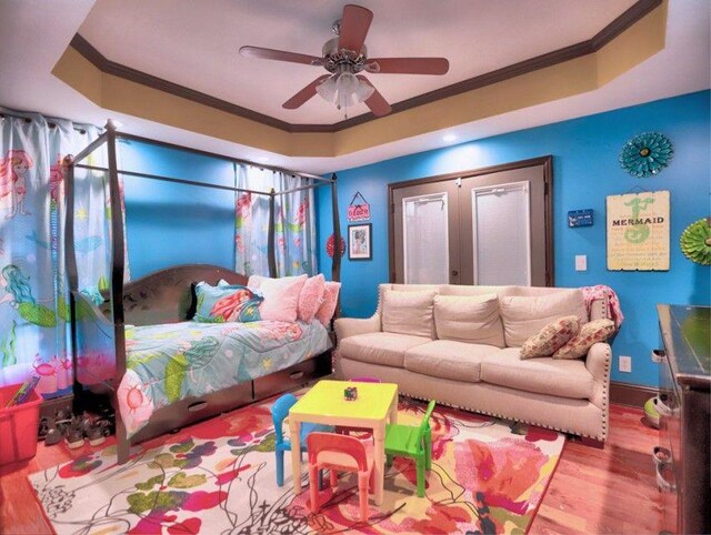 interior space featuring crown molding, a ceiling fan, wood finished floors, and a raised ceiling