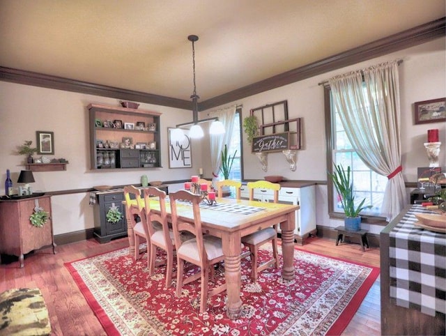 dining area featuring crown molding, baseboards, and wood finished floors