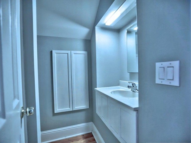 bathroom featuring baseboards, lofted ceiling, wood finished floors, and vanity