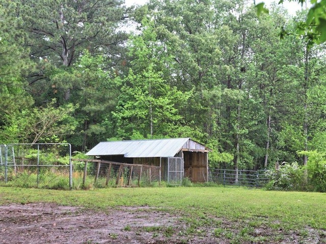 view of yard with fence, an outdoor structure, an outbuilding, and a wooded view
