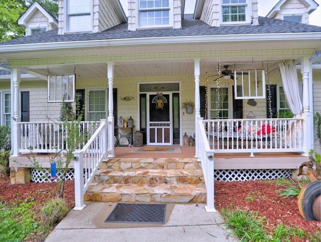 property entrance with a ceiling fan, roof with shingles, and covered porch