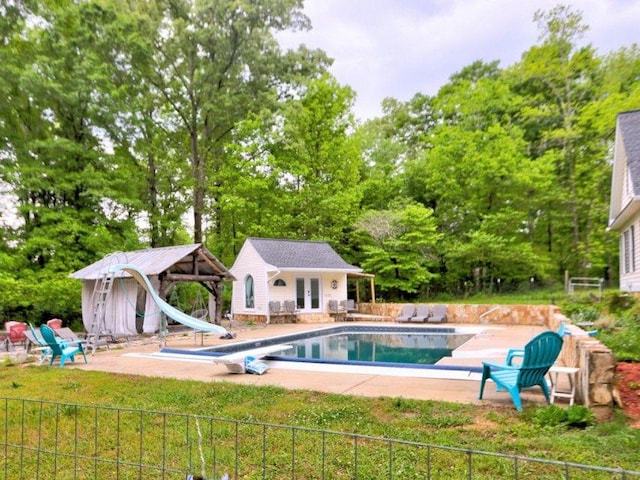 view of swimming pool with a diving board, a patio, a water slide, a storage structure, and an outdoor structure