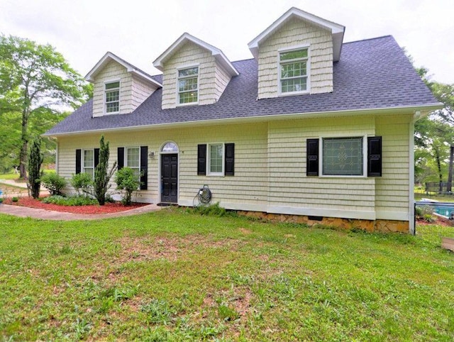 cape cod-style house featuring roof with shingles and a front lawn