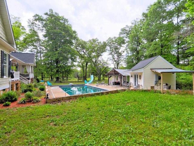 pool with a patio area, a gazebo, a diving board, a water slide, and a yard