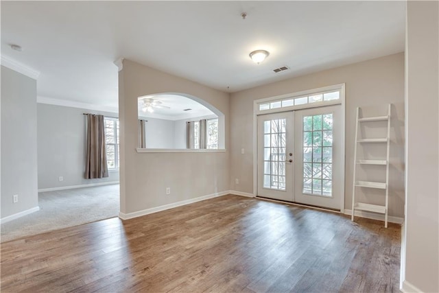 interior space with arched walkways, wood finished floors, visible vents, baseboards, and french doors