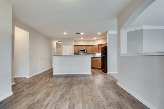 kitchen featuring dark countertops, stainless steel microwave, light wood-style floors, freestanding refrigerator, and baseboards