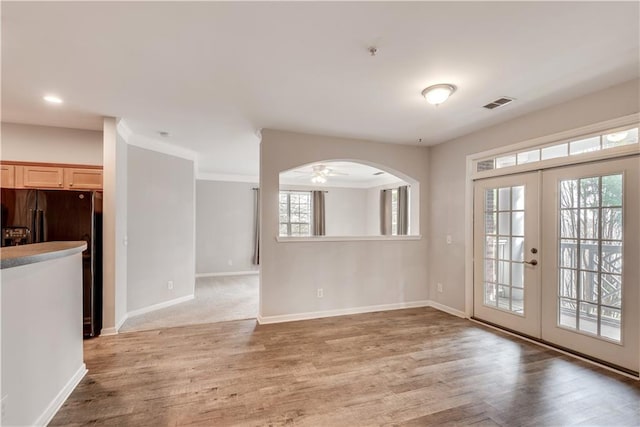 unfurnished room featuring arched walkways, french doors, visible vents, and baseboards