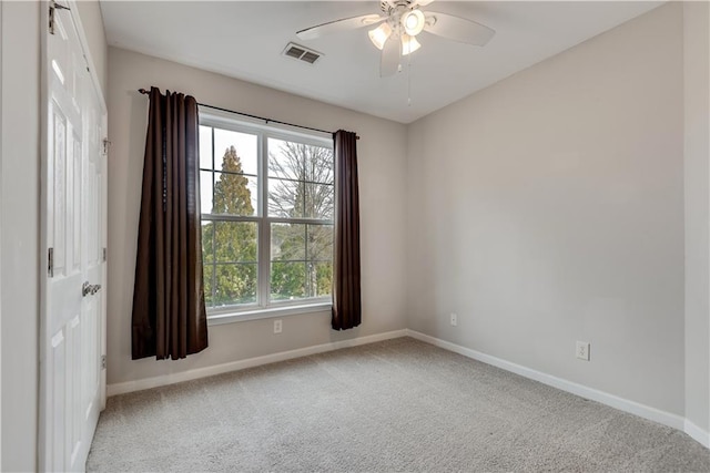 spare room featuring carpet floors, visible vents, and baseboards