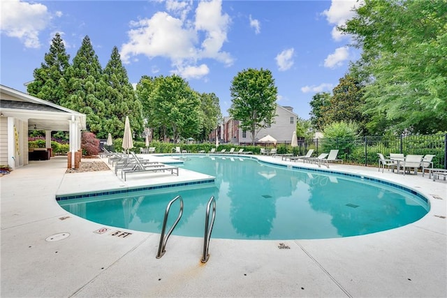 community pool with a patio and fence