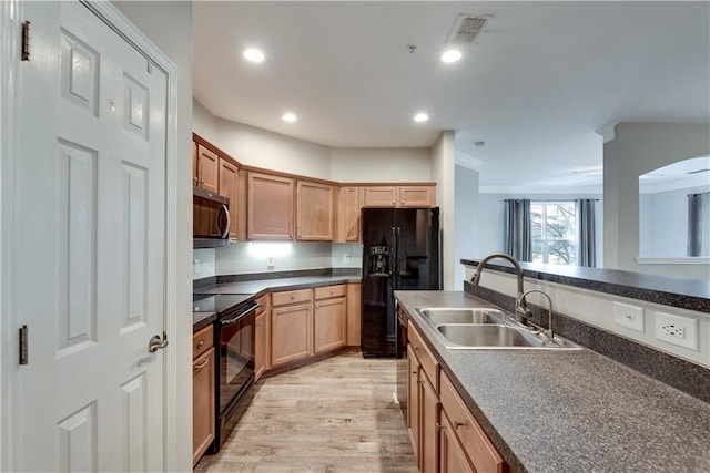 kitchen with a sink, visible vents, light wood-type flooring, black appliances, and dark countertops