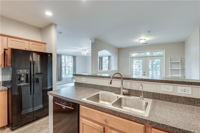 kitchen featuring dark countertops, light wood-style flooring, light brown cabinetry, a sink, and black appliances