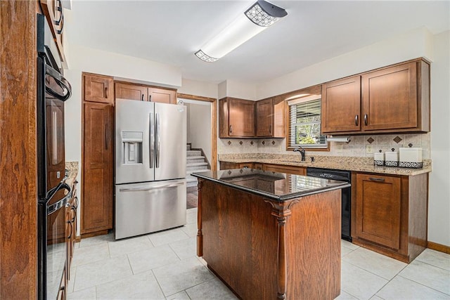 kitchen with light tile patterned flooring, a kitchen island, backsplash, dark stone counters, and black appliances