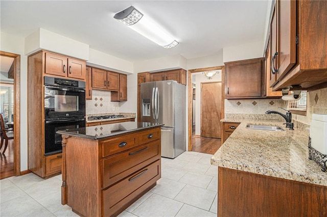 kitchen featuring light stone counters, light tile patterned floors, stainless steel appliances, a kitchen island, and a sink