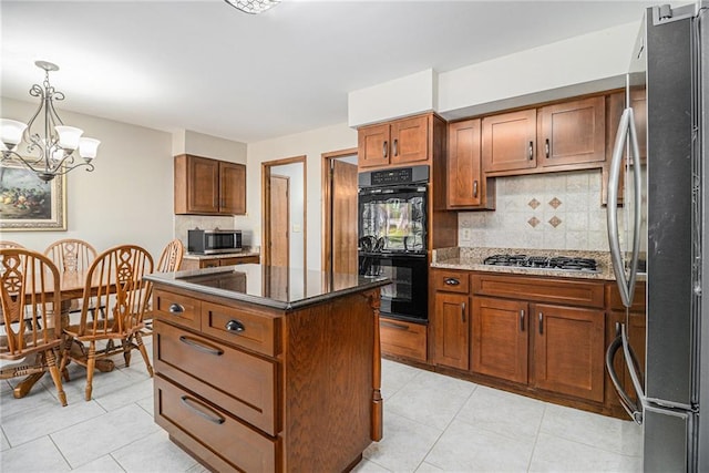 kitchen featuring brown cabinetry, dark stone counters, a kitchen island, appliances with stainless steel finishes, and backsplash