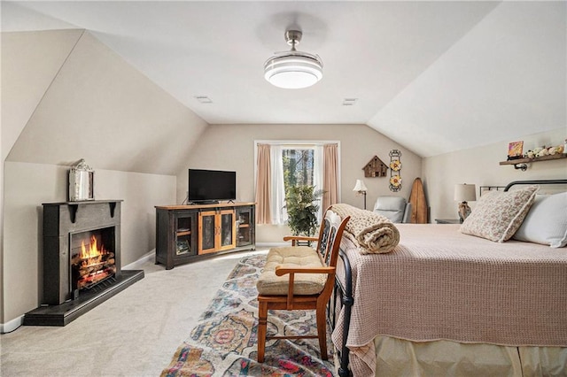 bedroom featuring a lit fireplace, carpet floors, lofted ceiling, and baseboards