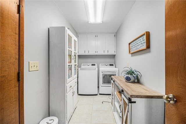 washroom featuring cabinet space, light tile patterned floors, and washer and dryer