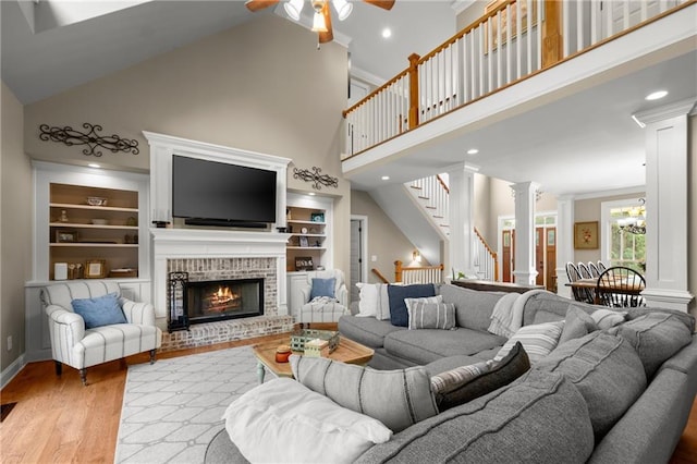 living room with high vaulted ceiling, wood finished floors, ceiling fan, built in features, and a fireplace