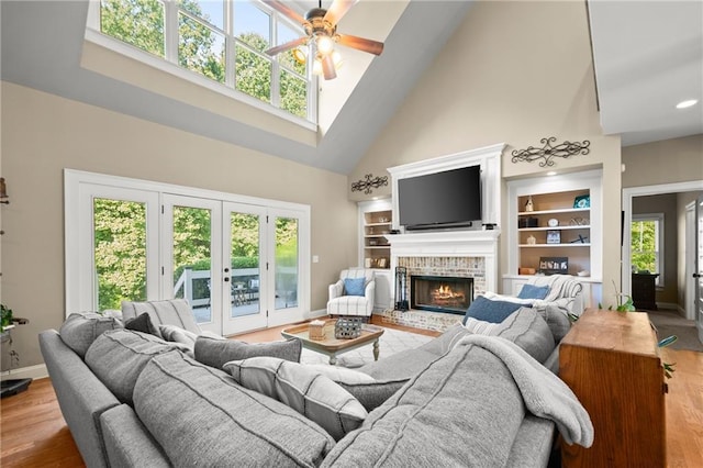 living area with wood finished floors, a ceiling fan, baseboards, and high vaulted ceiling