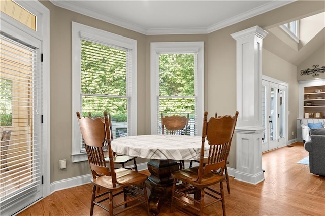 dining room with baseboards, ornamental molding, light wood finished floors, and ornate columns