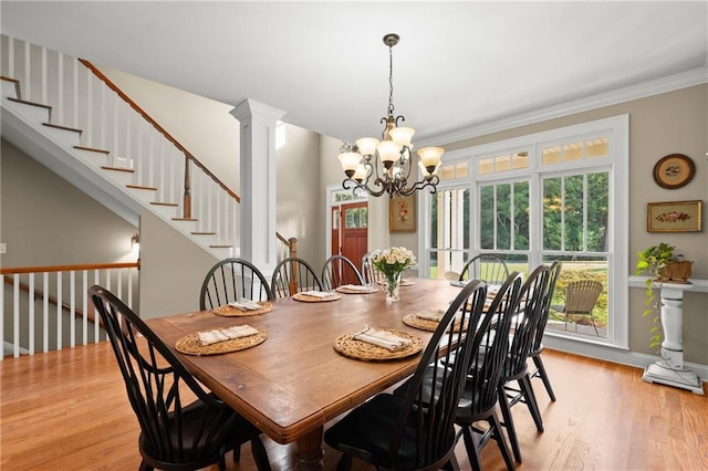 dining area featuring light wood-style flooring, decorative columns, baseboards, a notable chandelier, and ornamental molding