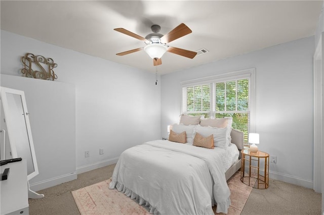 carpeted bedroom featuring baseboards, a ceiling fan, and visible vents