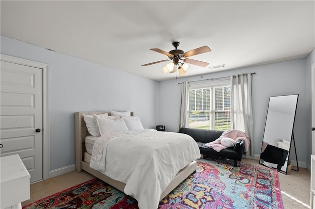 bedroom with visible vents, a ceiling fan, baseboards, and light carpet