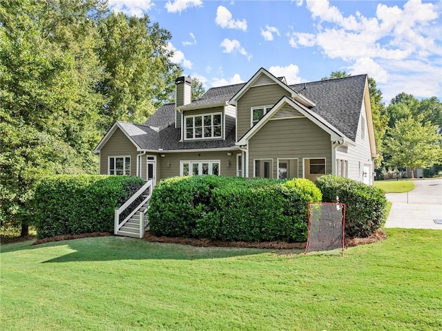 craftsman-style home featuring a shingled roof, a front yard, and a chimney