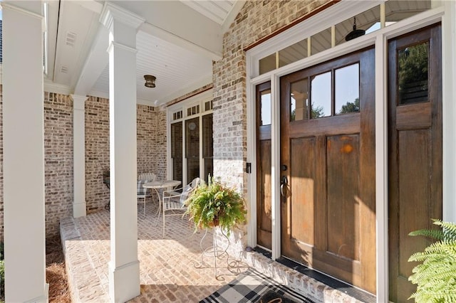 doorway to property with covered porch, brick siding, and outdoor dining space