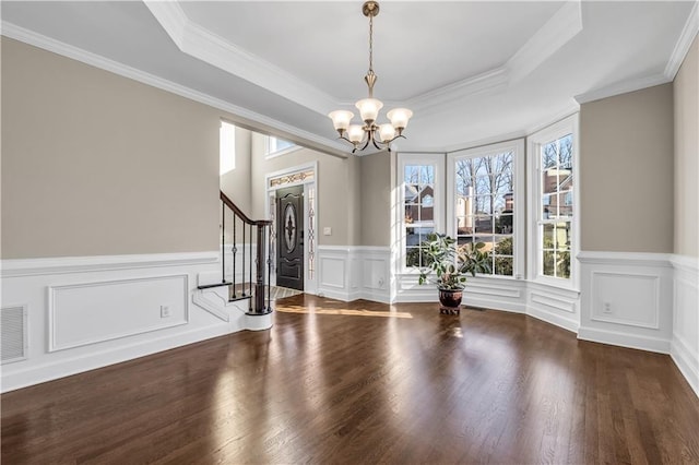 interior space featuring a raised ceiling, ornamental molding, dark hardwood / wood-style flooring, and an inviting chandelier