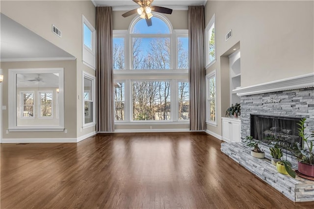 unfurnished living room featuring a fireplace, built in features, crown molding, and dark hardwood / wood-style flooring