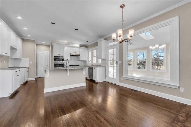 kitchen with a chandelier, decorative light fixtures, a skylight, backsplash, and white cabinetry