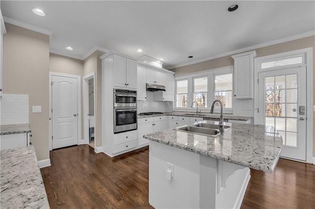 kitchen with light stone countertops, dark hardwood / wood-style floors, an island with sink, tasteful backsplash, and white cabinetry