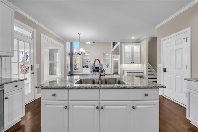 kitchen featuring sink, white cabinetry, hanging light fixtures, and an island with sink