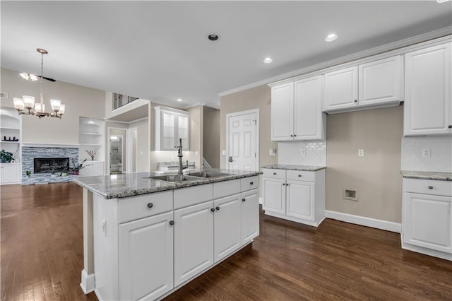 kitchen featuring white cabinets, a stone fireplace, and light stone countertops