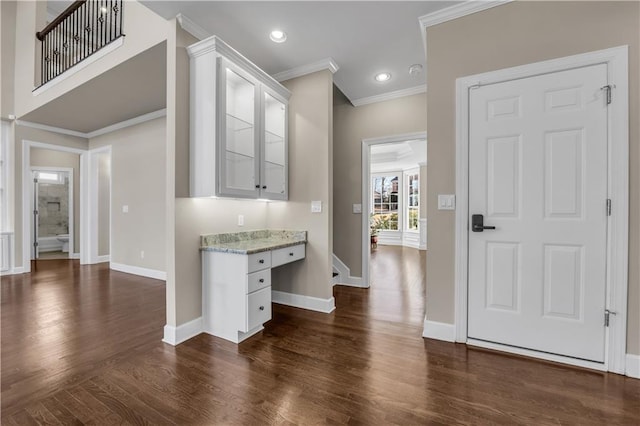 interior space with built in desk, dark hardwood / wood-style flooring, and crown molding