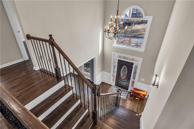 entrance foyer with a high ceiling, dark wood-type flooring, and an inviting chandelier