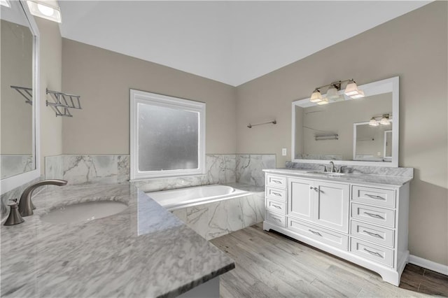 bathroom with vanity, tiled bath, and hardwood / wood-style flooring